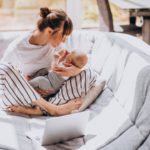 Young mother with her kid working at home on a computer