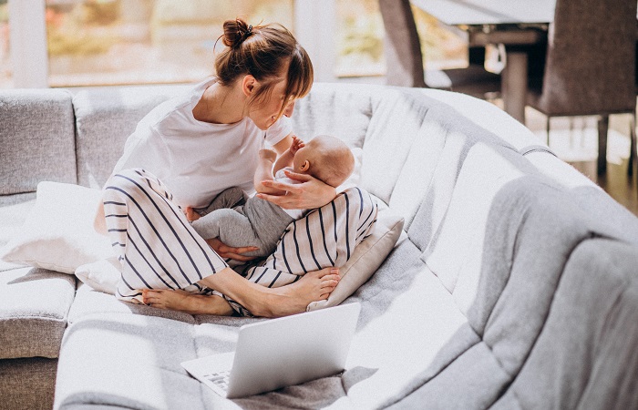 Young mother with her kid working at home on a computer