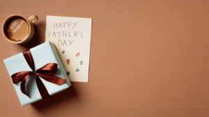 Minimalist Father's Day composition with gift box, card and coffee on brown background sentimental father's day gifts