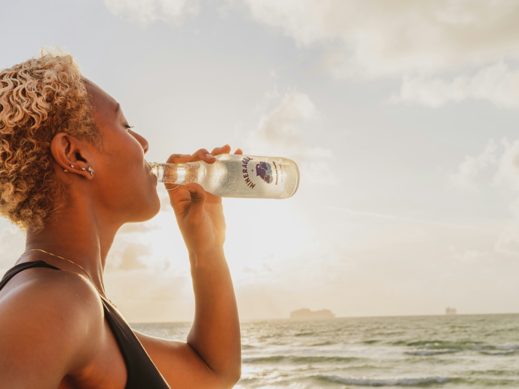 woman drinking water on the beach what to wear in 90 degree weather