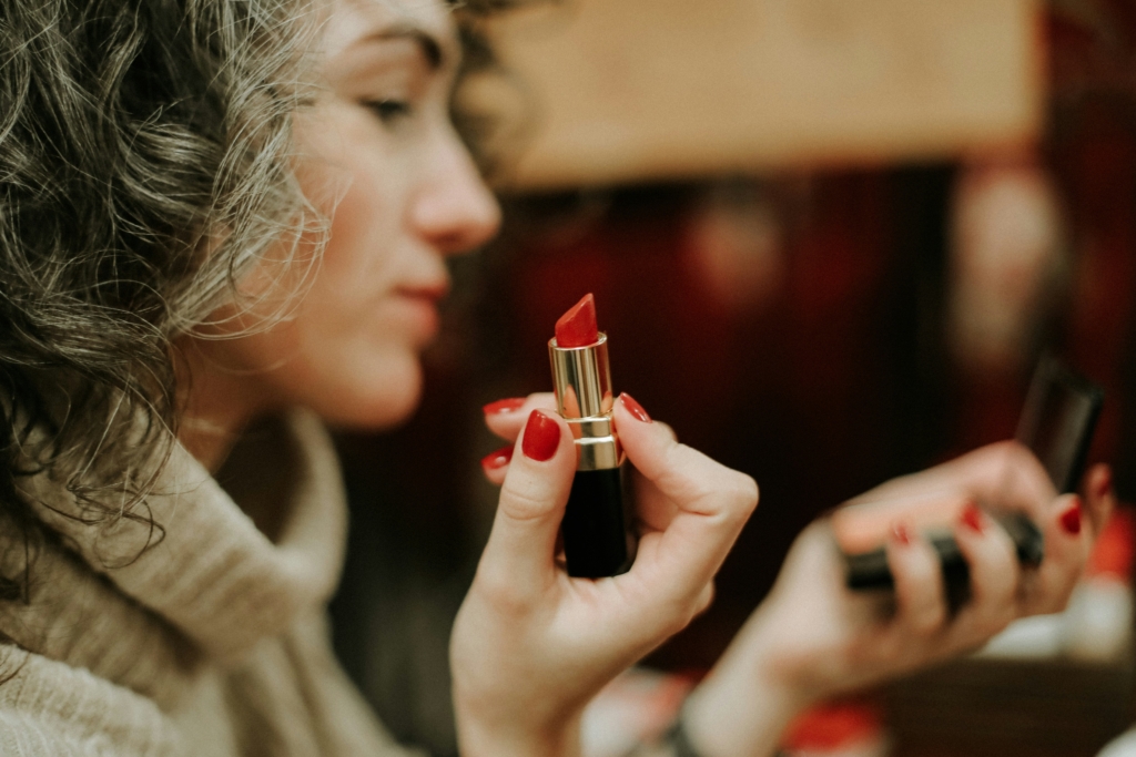 woman putting on lipstick fall beauty trends 2026