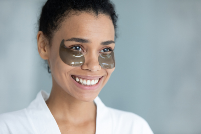 best drugstore eye cream for dark circles Close up of smiling biracial young woman use apply under eye gel patches for healthy glowing skin, happy african American female do facial beauty procedures in bathroom, skincare, cosmetology concept makeup skincare beauty