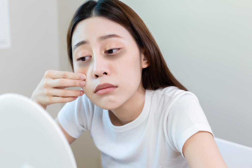 Asian young female stress looking mirror check have dark eye circles on face from staying up sleepy late. from hard work, no time to sleep. best drugstore eye cream for dark circles
