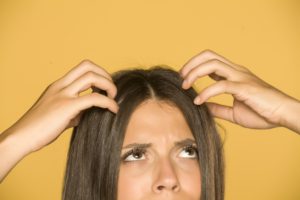 Beautiful young woman with itchy scalp on yellow background dr