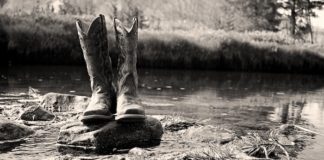 Grayscale Photo of Cowboy Boots on Rock - dresses to wear cowboy boots with