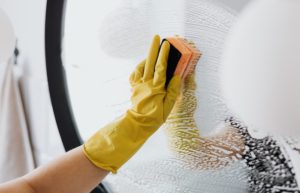 Faceless person cleaning mirror with sponge - housekeeper jobs