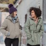Diverse women in warm clothes walking on street - cute snow outfits