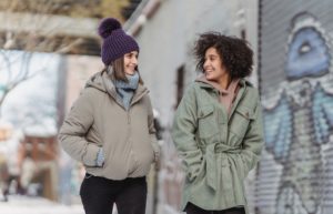Diverse women in warm clothes walking on street - cute snow outfits