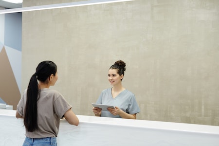 A Receptionist Smiling at a Person - part time receptionist jobs