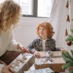 A Boy Holding a Present with his Mom on Christmas - gift guides for kids in 2022