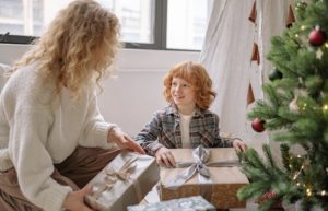 A Boy Holding a Present with his Mom on Christmas - gift guides for kids in 2022