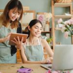 Happy women working on gadgets in floral store - creative jobs near me