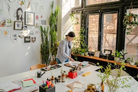 Craftswoman working with drafts at table with stationery in workshop - creative jobs near me