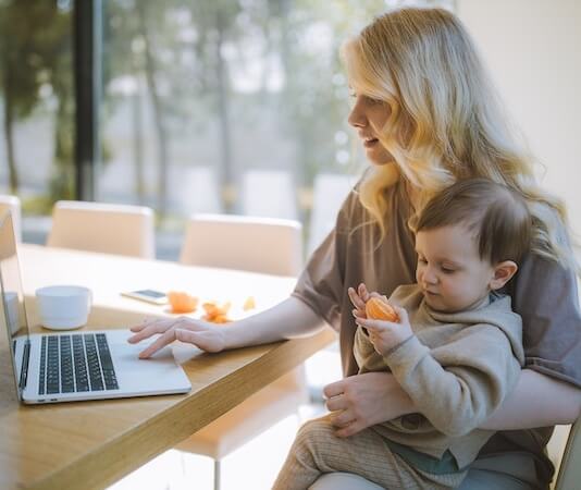 Woman Carrying her Baby and Working on a Laptop - work from home outfits