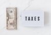 American dollar bills and vintage light box with inscription - tax prep for small business