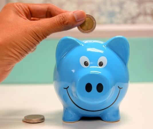 Person Putting Coin in a Piggy Bank - planning for recession