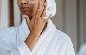 Woman applying cosmetic cream on face - biotin vs. collagen