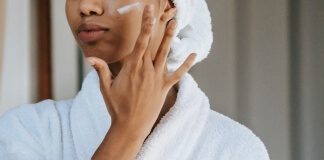 Woman applying cosmetic cream on face - biotin vs. collagen