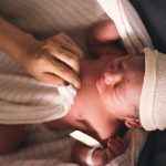 Person Covering Infant With Swaddling Blanket