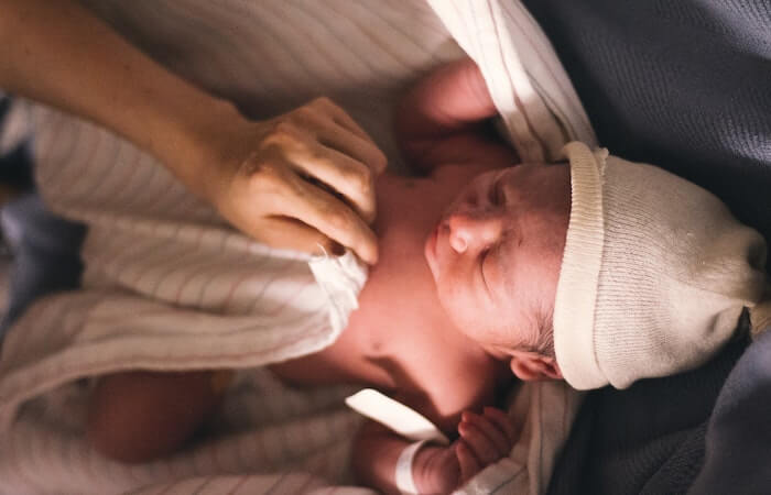 Person Covering Infant With Swaddling Blanket