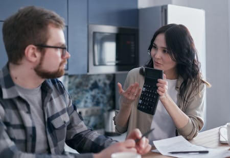 tax planning woman holding calculator talking to man