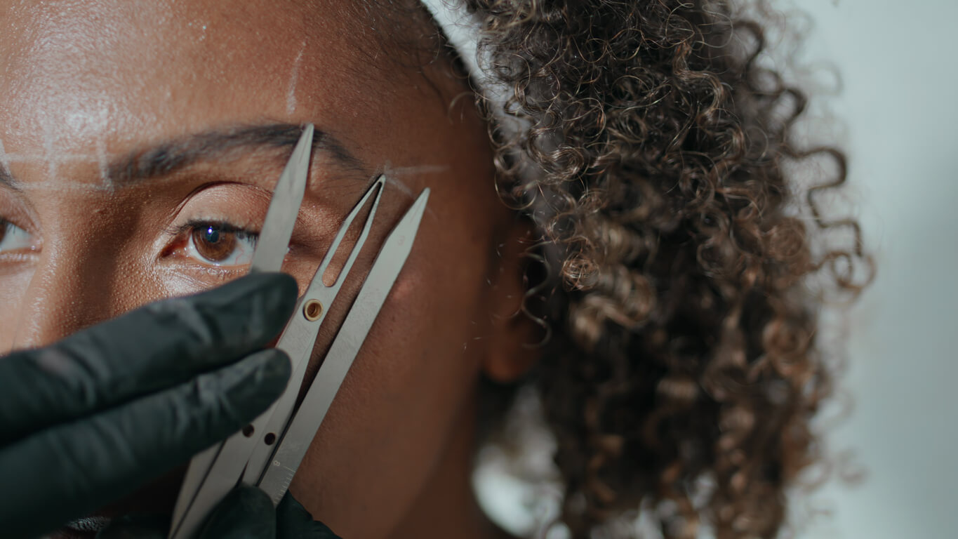skin mapping - Closeup hands marking brows for permanent makeup. African american visit beauty salon. Unknown cosmetologist map analysing shape with ruler tool in clinic. Microblading correction technique concept.