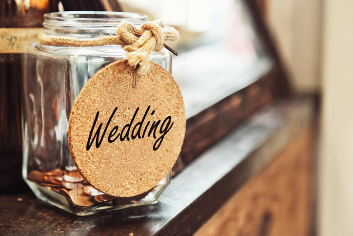 wedding stationary Vintage retro glass jar with hemp rope tie wedding tag and few coins inside on wood counter concept of saving money for wedding