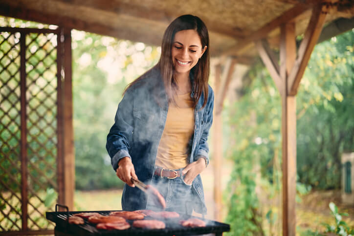 deals on meat deliver A brunette girl making a barbecue outdoors, putting a slice of meat on the grill. woman grilling