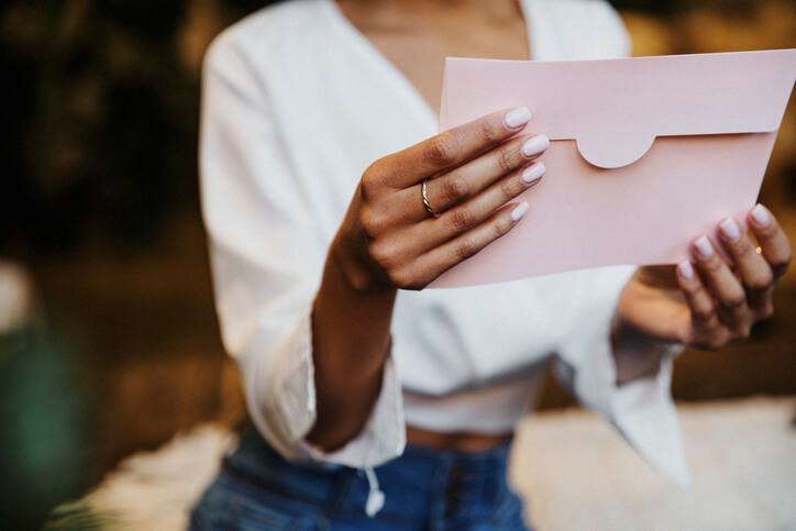 Woman reading a wedding invitation card when to send save the dates