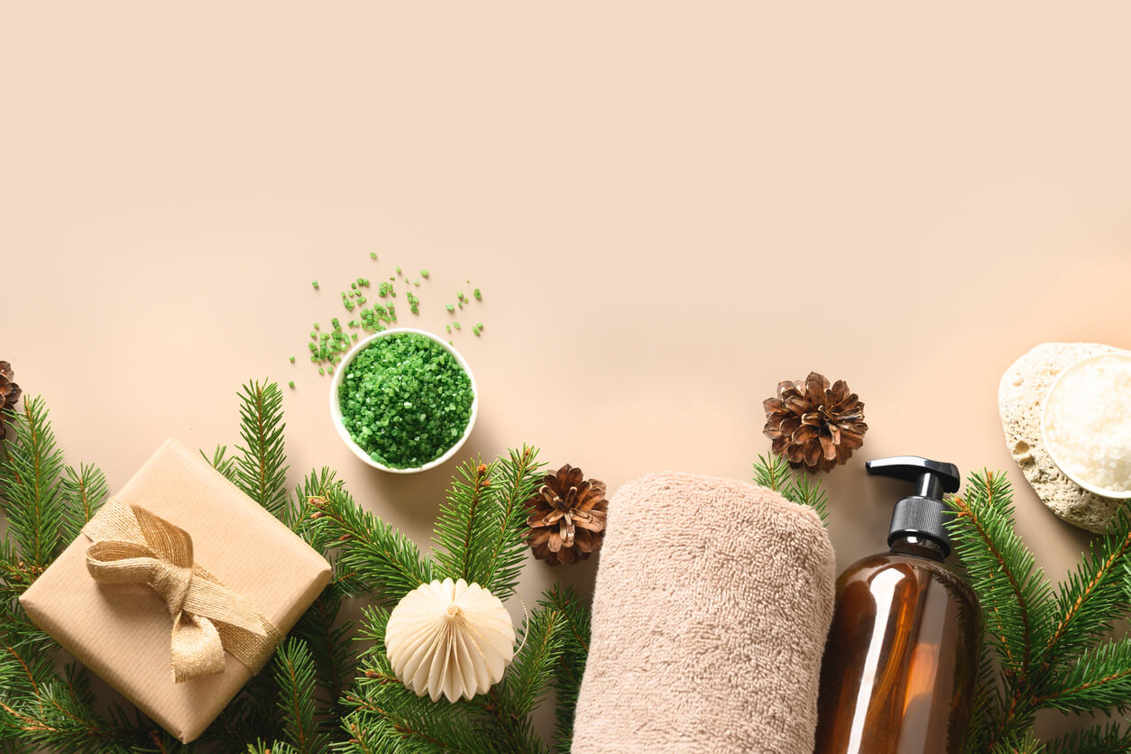 Christmas Spa concept with gift, wellness objects, cosmetic sea salt, towel, pine cones on beige natural background. Festive winter holiday with healthy relaxation, harmony for mental health. Natural skin care concept. wellness gifts for christmas