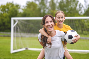soccer mom outfits A happy mother playing football outdoor on a summer day with her daughter