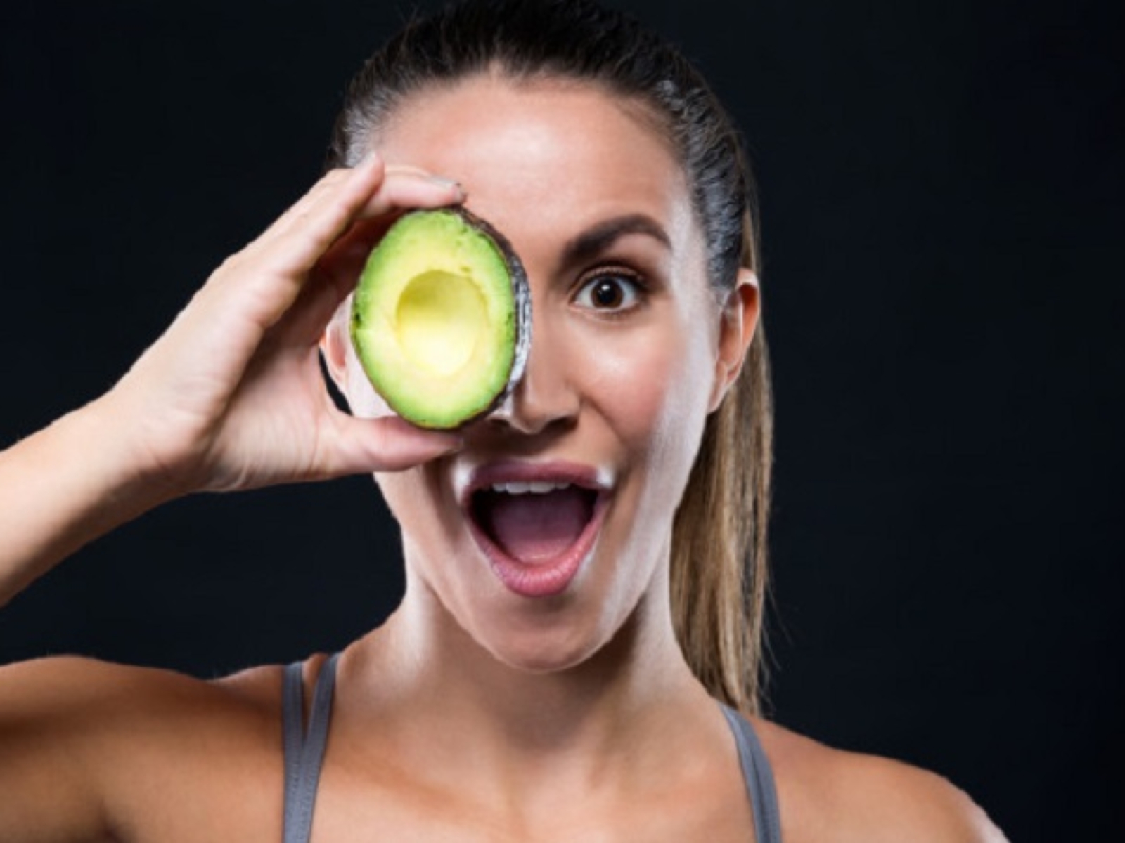 beautiful-young-woman-holding-avocado-over-black-background_1301-7565